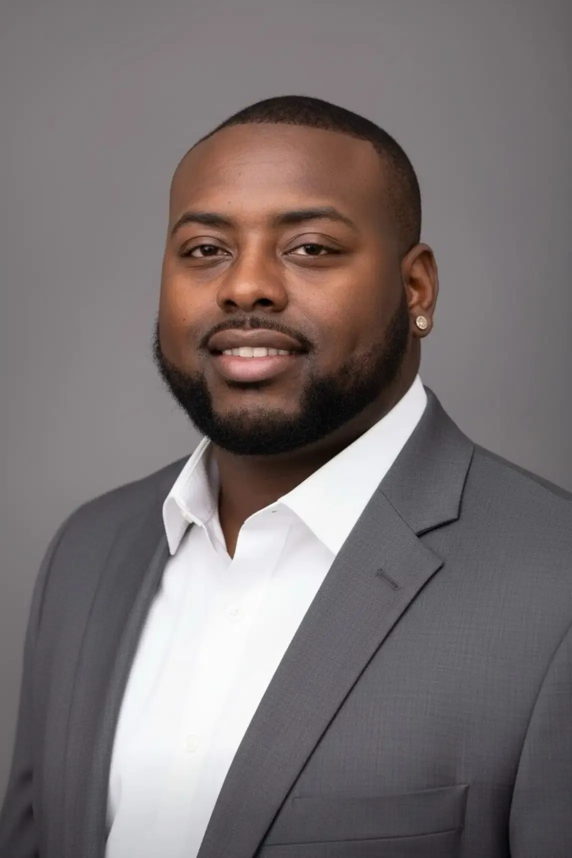 Joshua Blackburn, president of HOME-WORK, smiling in a grey suit and white shirt against a grey studio background